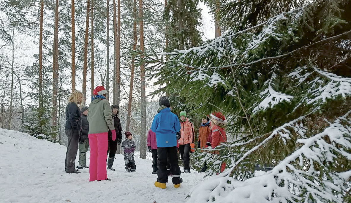 Luminen metsä, jossa seisoo ympyrässä ihmisiä.