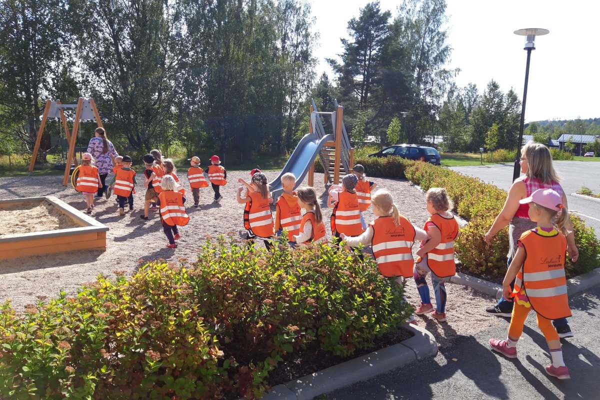 Lapsia menossa leikkikentälle huomioliivit päällä.